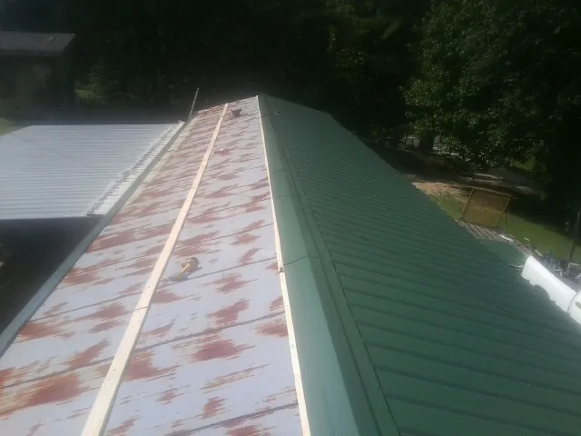 Old rusted panels beside newly installed green metal roofing — Wind Damage Roof Repair by Roofing Brothers in Fishertown