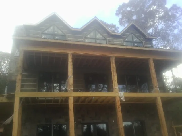 Dormers and porch framing on a large log home under construction — Roof Coating work by our crew in Fishertown