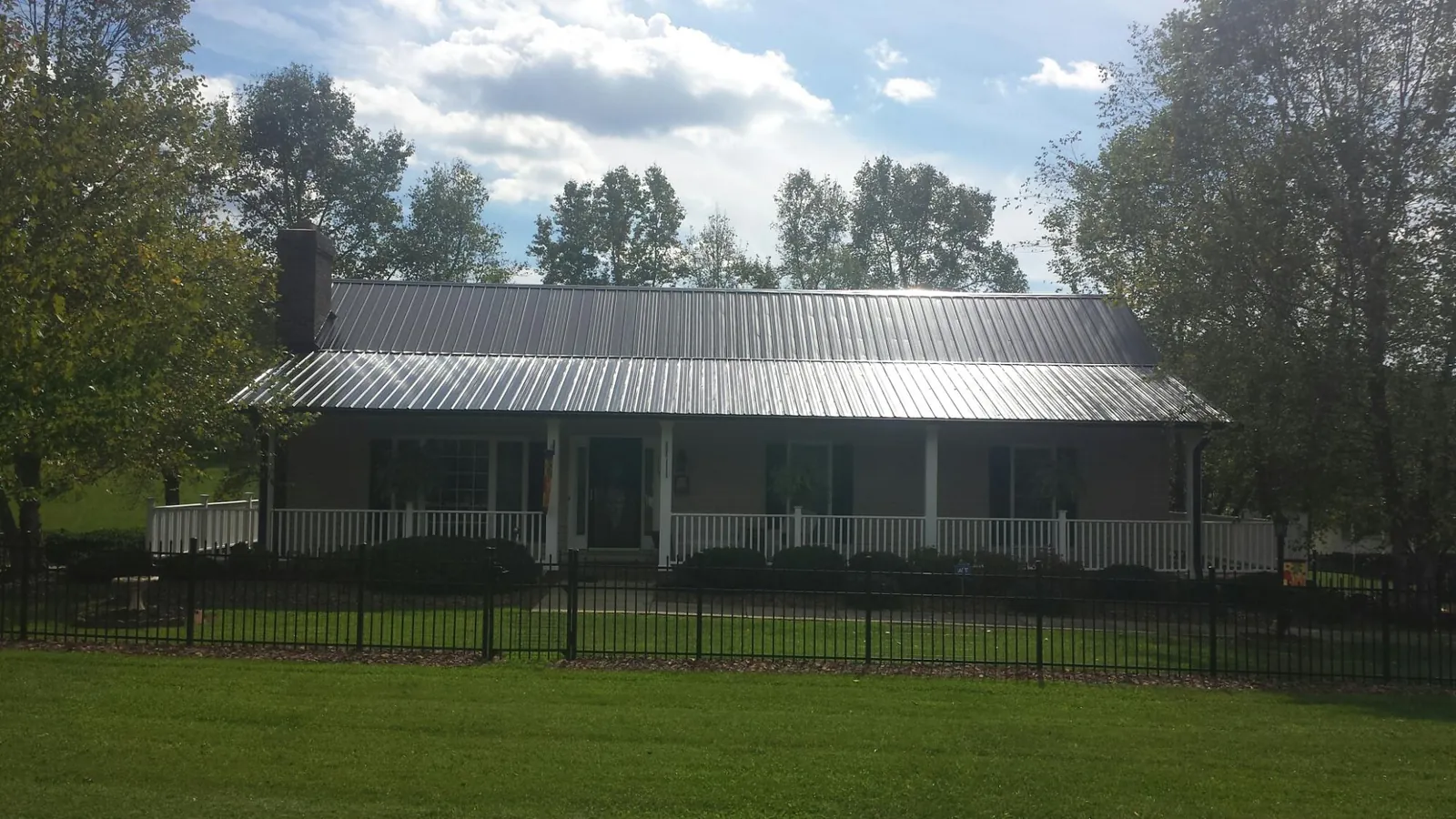 Gray metal roof on a brick ranch with a full width front porch — Gutter Guard Installation work by our crew in Fishertown