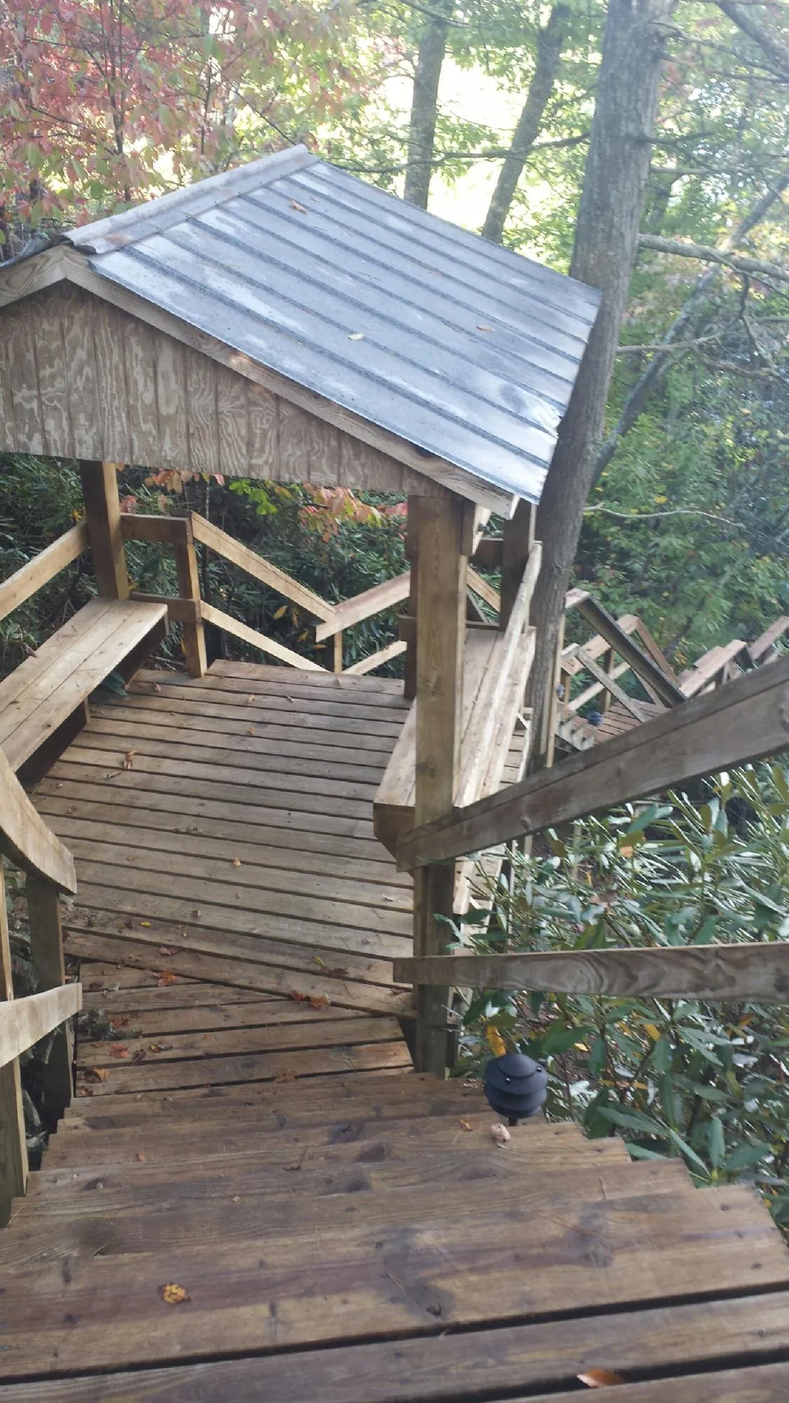 Metal roofed shelter over wooden steps on a wooded walkway — Skylight Repair & Installation work by our crew in Fishertown