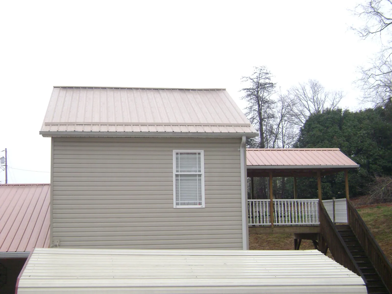 Tan metal roofs on a two story addition and attached porch, from a Roof Replacement job in Fishertown