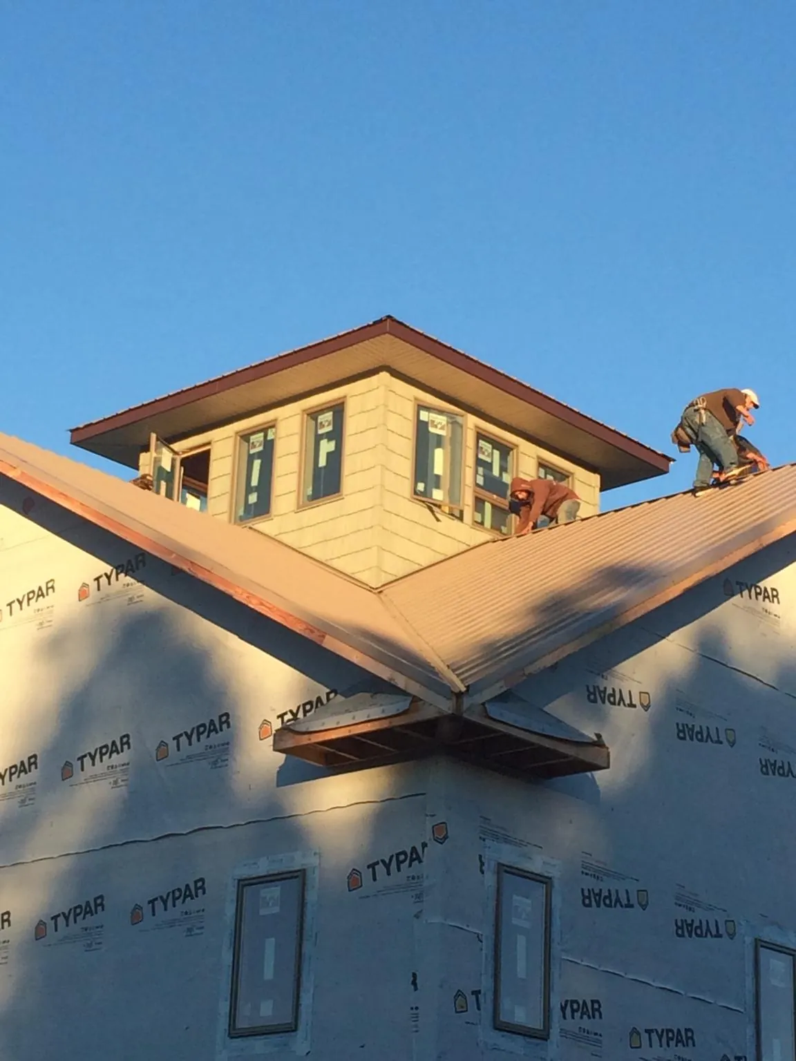 Roofers working around a rooftop cupola on a new metal roof at sunset — Roof Waterproofing in Fishertown by Roofing Brothers